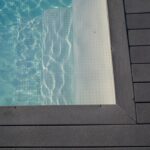 Piscine bordée de bois sous le soleil, terrasse extérieure