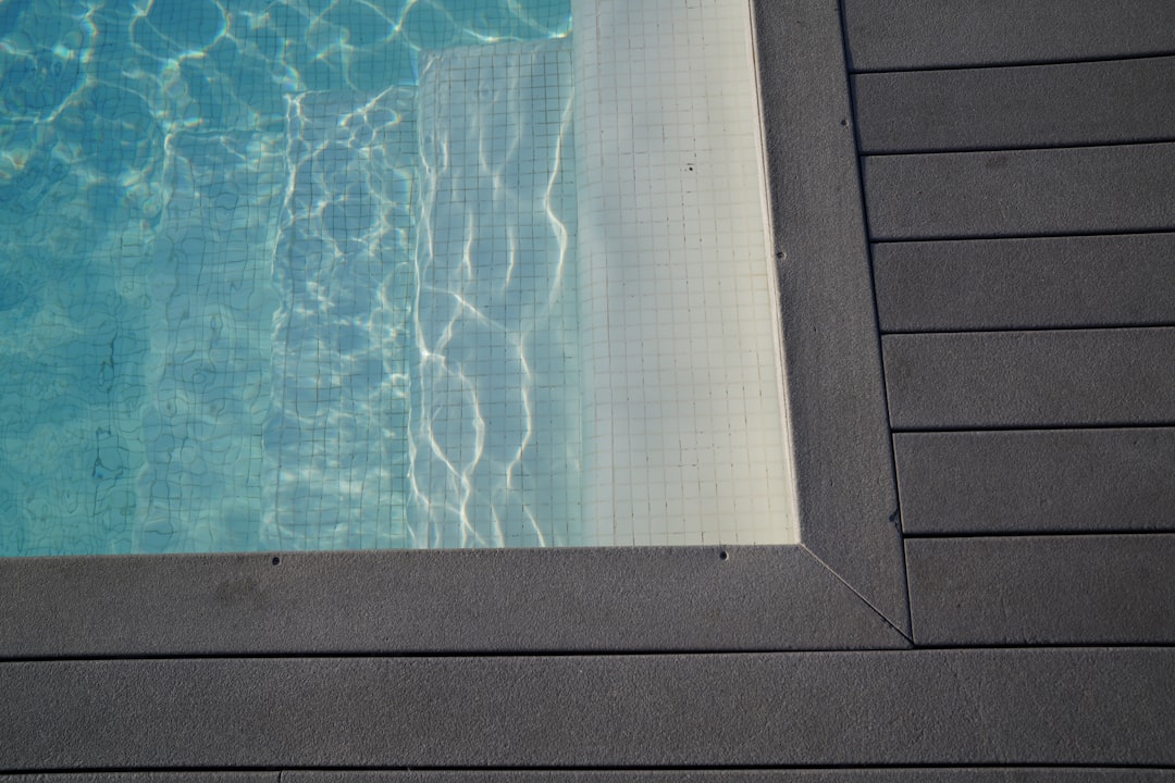 Piscine bordée de bois sous le soleil, terrasse extérieure
